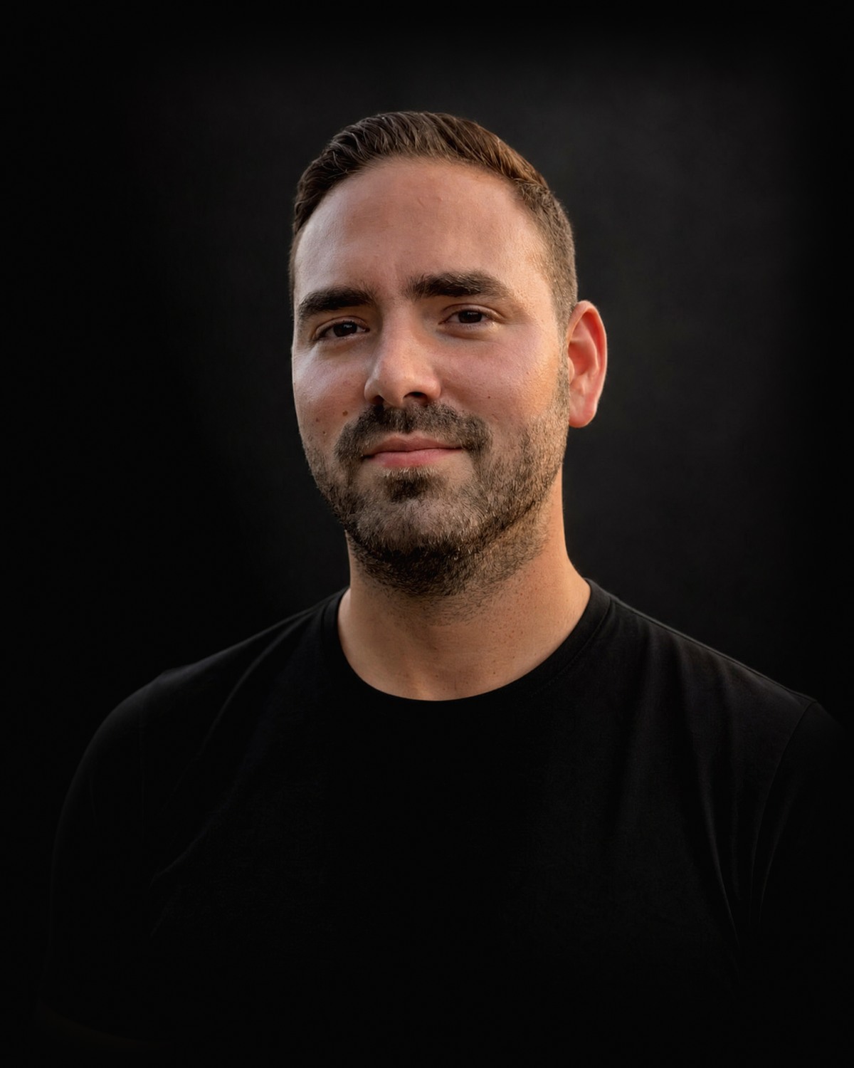 Daniel Szarka-Kovacs in a black t-shirt against a dark background.